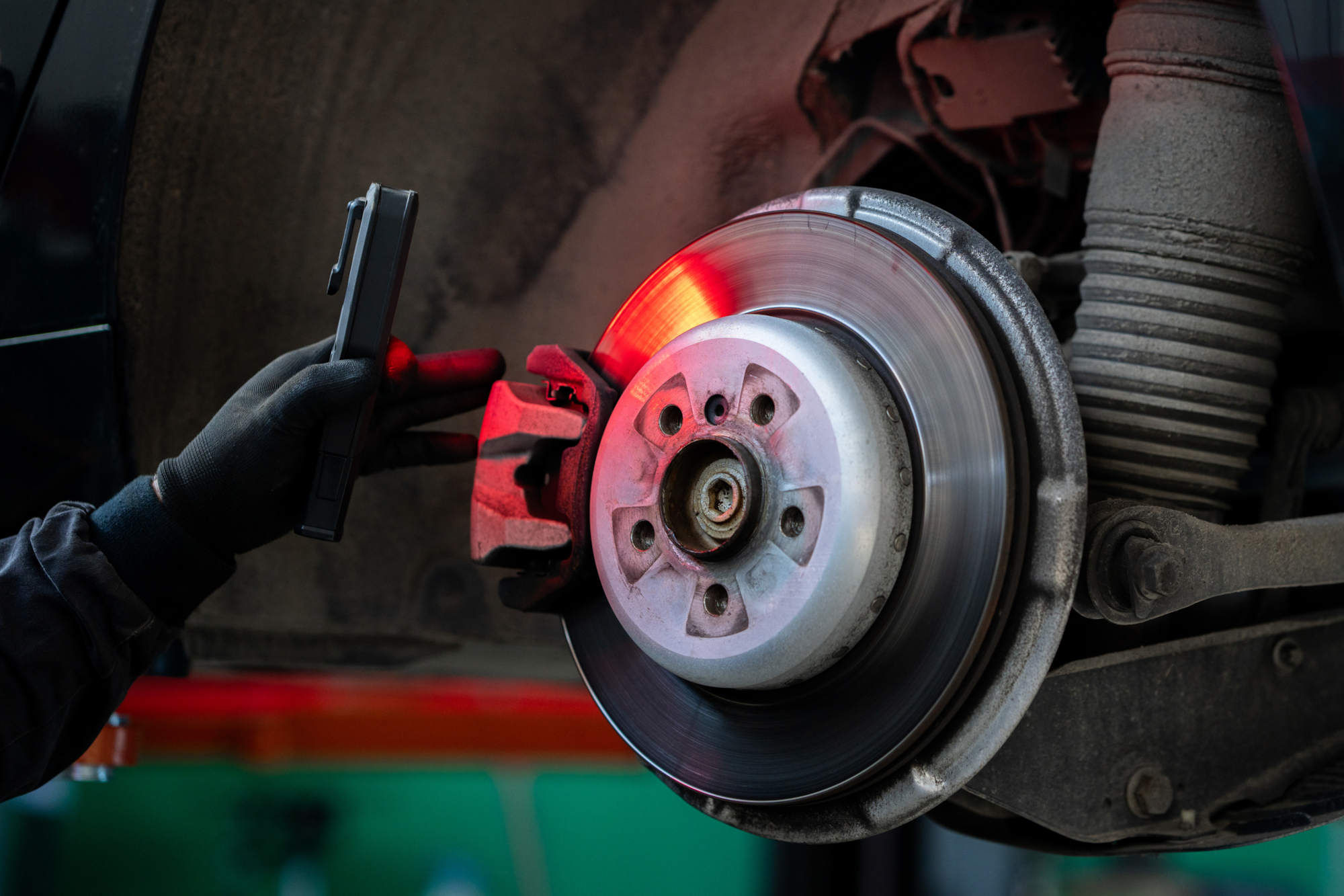 Close up of hands of serviceman checking the brake discs of a car.