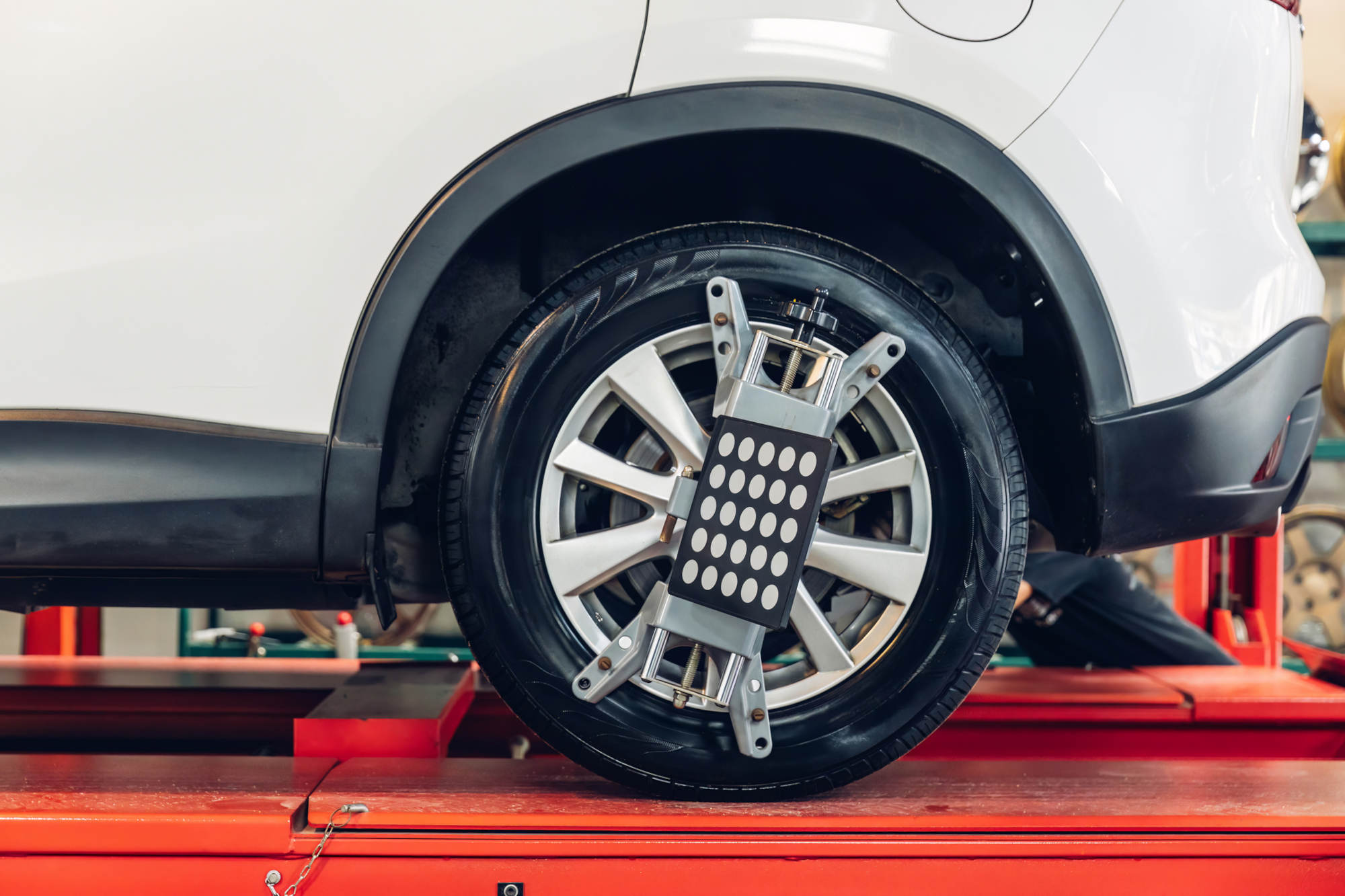 Car wheel centering machine adjustment. Auto service mechanic installing wheel alignment sensor on tire during vehicle suspension alignment adjustment Car wheel centering machine adjustment.