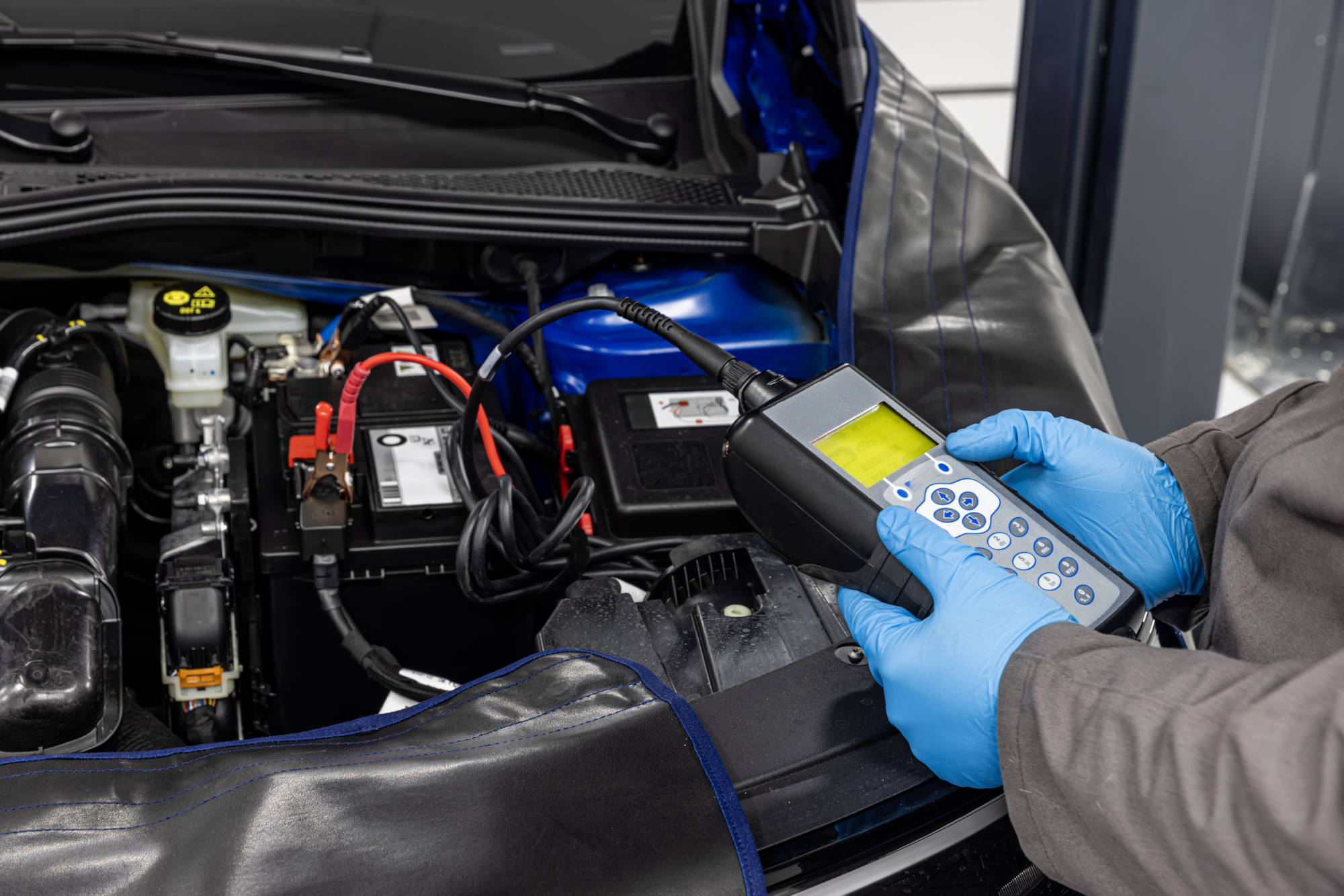 Car master mechanic checking and testing automotive battery with digital electronic battery tester
